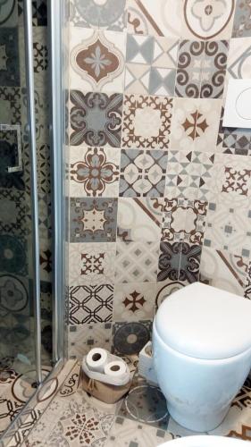 a bathroom with a toilet and a tiled wall at QuickHome La Torretta in Asti