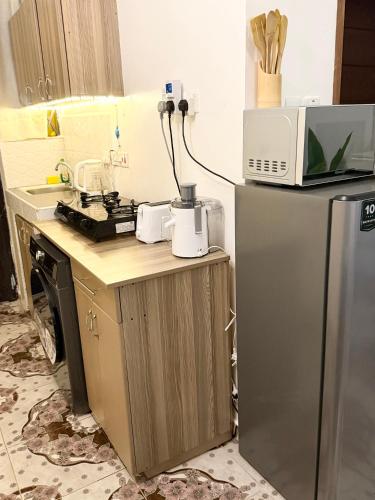 a kitchen with a microwave on top of a refrigerator at Raha Luxe Stays 2 in Entebbe