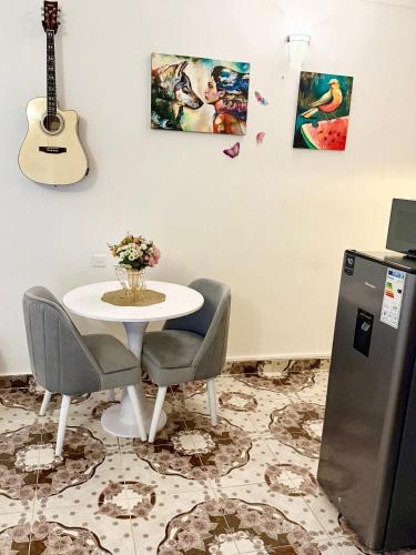 a table with chairs and a guitar on a wall at Raha Luxe Stays 2 in Entebbe