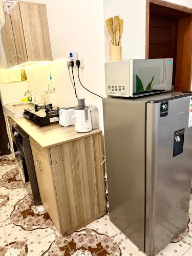 a kitchen with a microwave on top of a refrigerator at Raha Luxe Stays 2 in Entebbe
