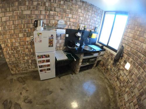 a kitchen with a refrigerator and a brick wall at Brandberg Tower Guesthouse in Uis