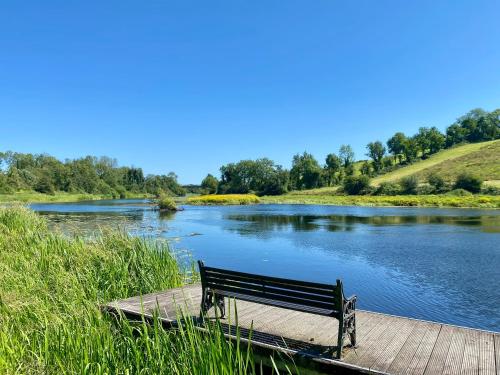 a bench sitting on a dock next to a river at Cois na hÉirne - Log Cabin I Lake View I Hot Tub in Belturbet