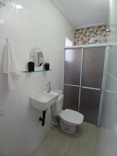 a white bathroom with a toilet and a sink at Aconchego e sossego in São Paulo