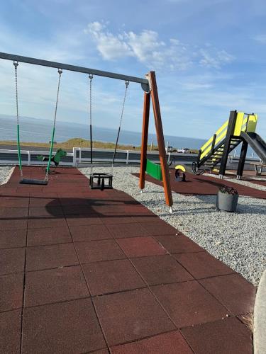 a playground with swings and a bench on the beach at Búlandshöfði family paradise in Grundarfjordur