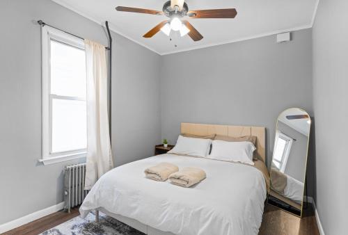 a bedroom with a bed with a ceiling fan and a mirror at Cozy Home, 19 min to NYC, 3 Car Driveway in Wallington