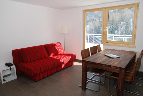 ein Wohnzimmer mit einem roten Sofa und einem Holztisch in der Unterkunft Chasa Sulai Appartements in Samnaun