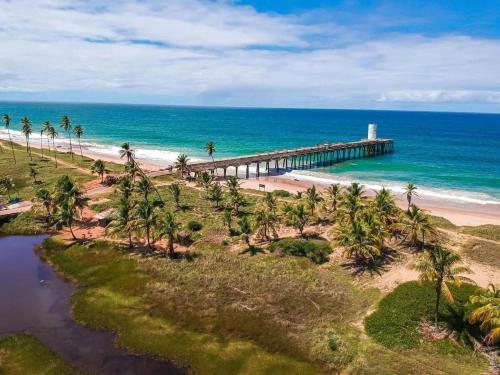 an aerial view of a pier on a beach with palm trees at Beach House in Camaçari