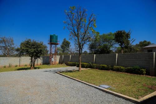 a fence with a tree and a water tower at Forest Views Haven - Flat 2 in Solwezi