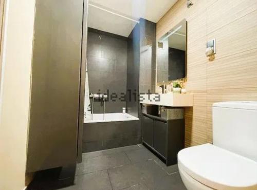 a bathroom with a toilet and a sink and a tub at Bajo con jardín 1min de la playa in Montgat