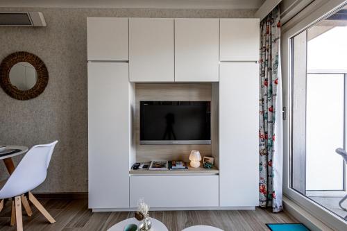 a living room with a tv and white cabinets at Studio met zeezicht in Middelkerke