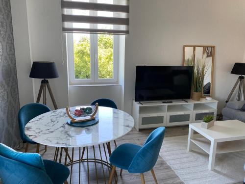 a living room with a table and chairs and a television at Les Rives des Habsbourg in Ensisheim