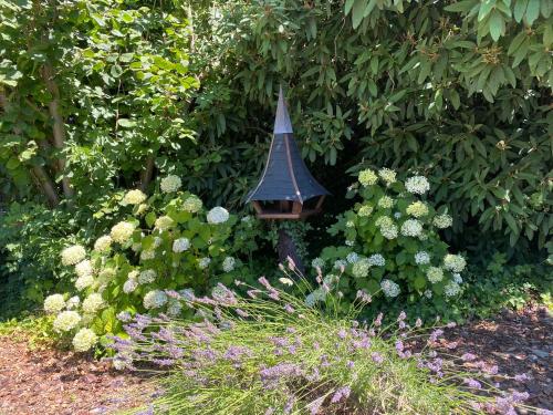a bird feeder in a garden with flowers at Les Rives des Habsbourg in Ensisheim