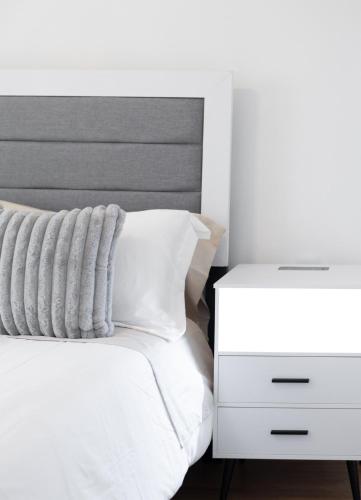 a white bed with a white nightstand and a white bedspread at Cozy Lodi Home ,23m to NYC, 3Car Driveway in Lodi