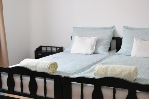 a bed with blue and white sheets and pillows at Ház a tónál Noszvaj in Noszvaj
