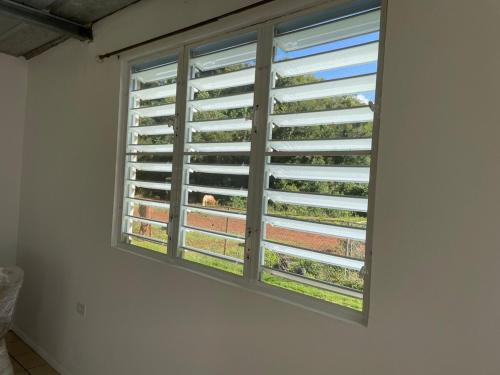 a window with shutters on a white wall at Arecibo's country cottage in Arecibo