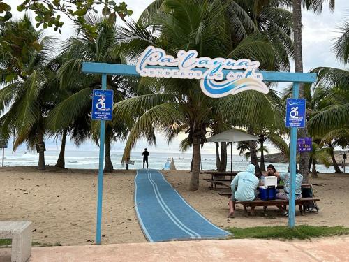 a person sitting on a bench next to a slide at the beach at Arecibo's country cottage in Arecibo