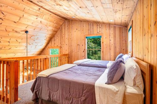 Un dormitorio con dos camas en una cabaña de madera. en River Fishing Cabin, en Lakemont