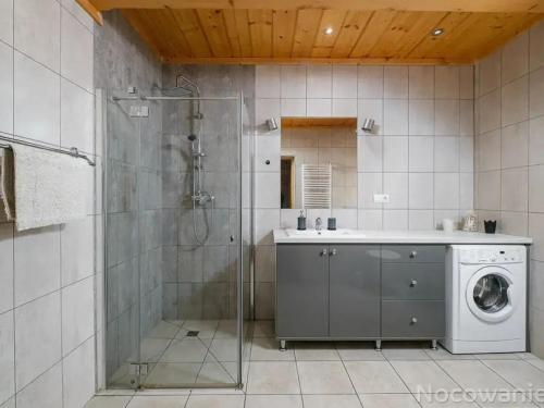a bathroom with a shower and a washing machine at Chaty u Bibra in Sablówka