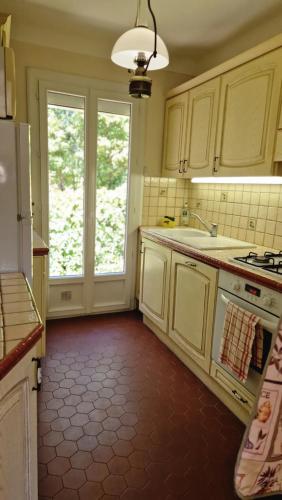 a kitchen with white cabinets and a red floor at Villa Les Chênes - Golf de Saint-Tropez Experience in Port Grimaud