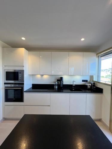 une cuisine avec des armoires blanches et un comptoir noir dans l'établissement Celeste Cannes Centre 700m du Palais des Festivals, à Cannes