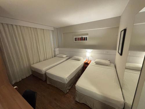 a hotel room with two beds and a lamp at Intercity BH Expo in Belo Horizonte