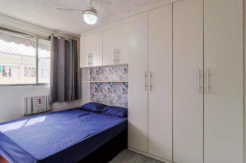 a bedroom with white cabinets and a blue bed at Apto com ar-condicionado e vaga em Honorio Gurgel in Rio de Janeiro