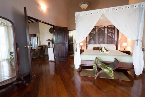a bedroom with a large bed with a canopy at Popa Paradise Beach Resort in Buena Vista