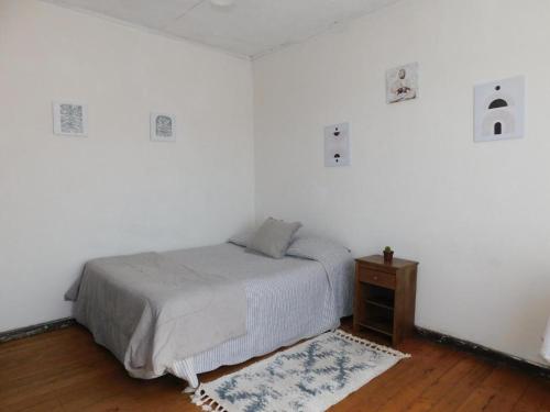 a white bedroom with a bed and a wooden floor at Wind Guest House in Valparaíso