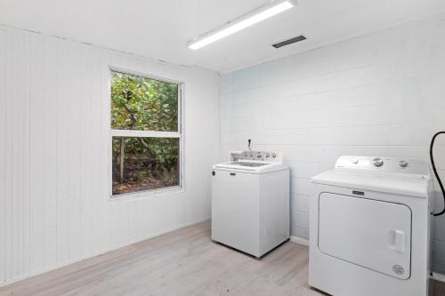 a white laundry room with a washer and a window at The Hideaway Cottage at Palmview Inn of Sanibel in Sanibel