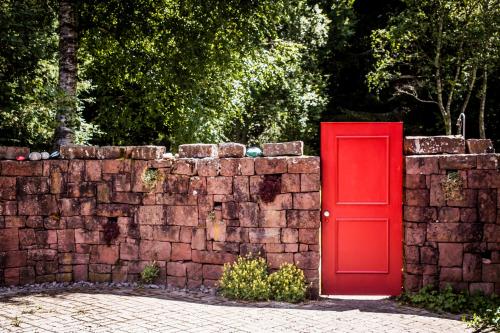 a red door next to a brick wall at Ferienwohnung am Hirschenmoor in Breitnau