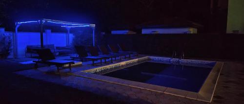 a pool with chairs and a table at night at Къща за гости ,,Ива'' in Bŭlgarevo