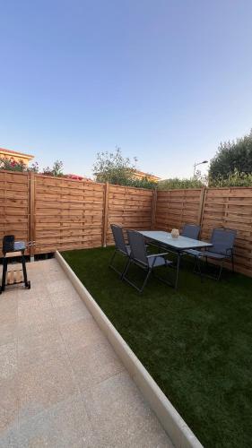 a patio with a table and chairs and a fence at Cocon Design avec jardin privé in Aimargues