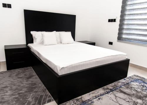 a bedroom with a large bed with white sheets and pillows at The Kottage Studio Apartment A in Accra