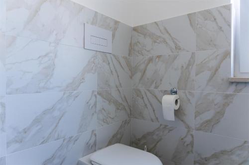 a bathroom with a white toilet and a marble wall at A Casa di Falco in Mondragone