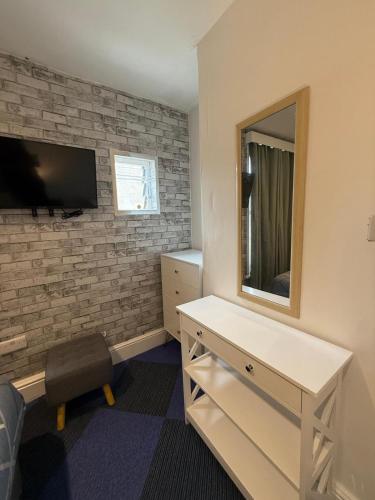 a room with a tv and a dresser and a mirror at Almar Hotel Apartments Blackpool in Blackpool