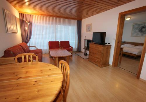 a living room with a table and a couch and a television at Résidence Mont-Calme in Nendaz