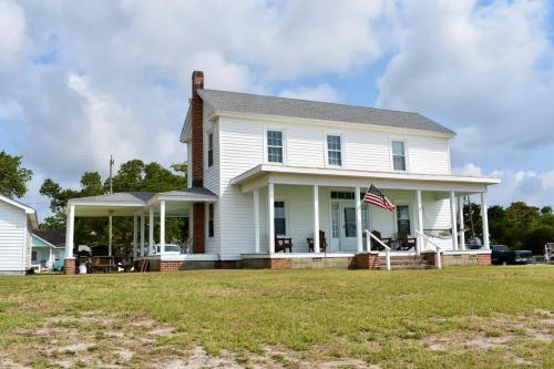 Una casa bianca con una bandiera americana di Comfortable Down East Waterfront Farmhouse a Sealevel