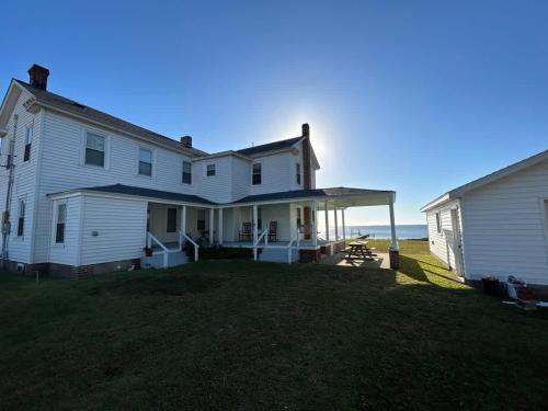 una casa bianca con un grande giardino vicino all'oceano di Comfortable Down East Waterfront Farmhouse a Sealevel