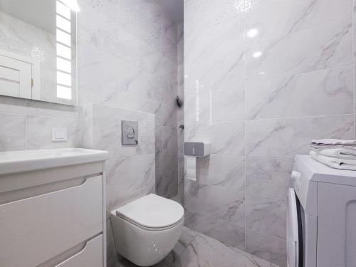 a white bathroom with a toilet and a sink at Апартаменты Kadorr 59 in Odesa
