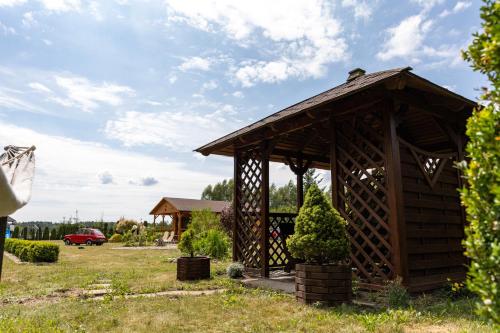 a small wooden pavilion in a field with a house at Jak u Dziadka 