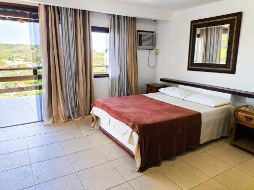 a hotel room with a bed and a window at Suites Buzios in Búzios
