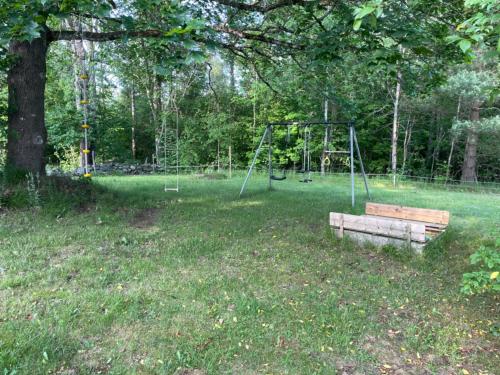 a park with a bench and a swing set at Villa Next to the Forest in Tingsryd