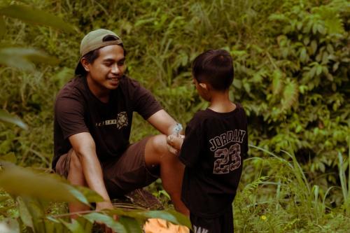 a man kneeling next to a young boy at Mimi homestay-LOMBOK in Tetebatu