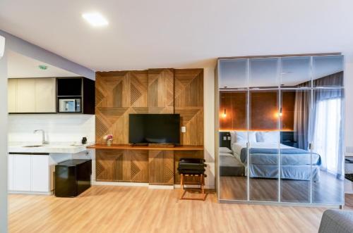 a kitchen and a bedroom with a bed and a television at Gran Paradiso Campos do Jordão By Ventura OFICIAL in Campos do Jordão