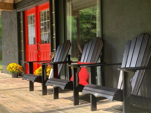 two chairs sitting on a porch with a red door at Muskoka Hutt in Huntsville