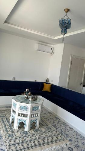 a living room with a table and a blue couch at Dar Omi Aïcha 2 in Kerkouene