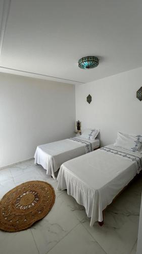 two beds in a room with a rug on the floor at Dar Omi Aïcha 2 in Kerkouene