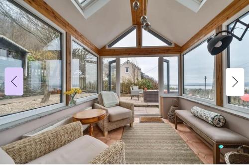 a conservatory with windows and a view of the ocean at 1 Engine Row Beautiful 3 Bedroom Cottage in Penclawdd