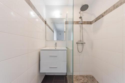 a white bathroom with a sink and a shower at Ciotat t2 in La Ciotat