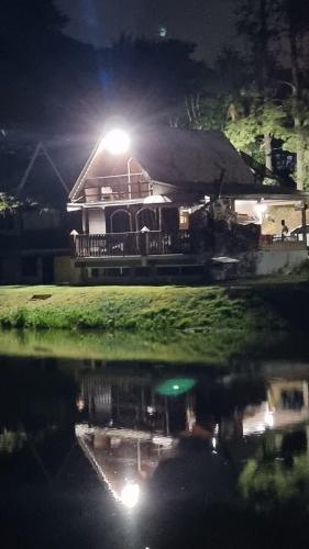 a house with a light on top of the water at night at Chalé do Lago in Pirapitingui